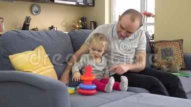 父亲带着孩子女儿在沙发上玩五颜六色的教育圈金字塔