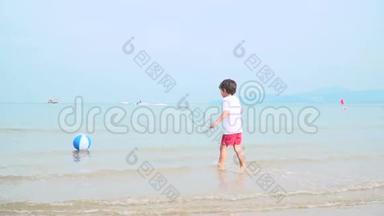 小男孩正在泰国美丽的沙滩上玩五颜六色的水球