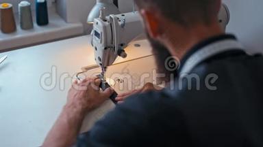 时尚胡子的裁缝正在时装设计室做缝纫机
