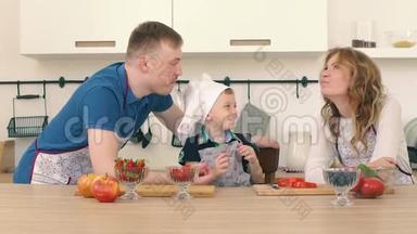 一家人正在厨房准备沙拉.. 儿子给爸爸妈妈喂草莓..