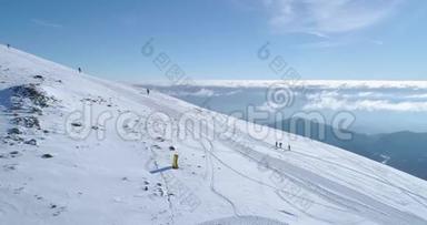 在冬季雪山滑雪跑道上，人们用雪鞋徒步旅行的侧面空中。 晴朗的阿尔卑斯山