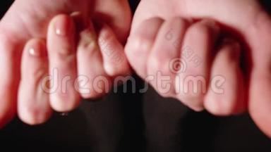 女人展示两个拳头，打开它们，展示张开的手掌中含有维生素。 黑色背景