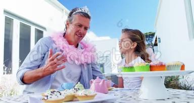 微笑的父亲和女儿穿着仙女服装参加茶会
