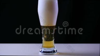 啤酒在黑色背景下倒入<strong>玻璃</strong>中。 气泡和泡沫在啤酒<strong>玻璃</strong>中迅速移动。 泡沫滑下<strong>玻璃</strong>
