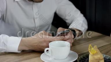 晚上，一个男人在咖啡馆里用手机输入信息。 他双手合拢。