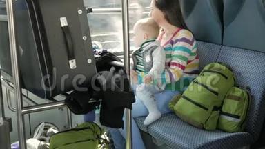 妈妈和宝宝坐在靠近窗户的移动火车上。 手提箱和背包放在年轻家庭附近