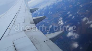 从飞机窗口可以看到飞机的翅膀，风景草地，田野，云彩。 一只鸟`眼睛