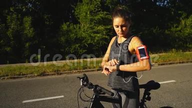 女人骑着一辆带智能手表心率监视器的自行车。 智能手表的概念。