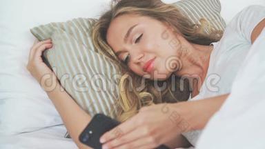 床上小玩意：女孩睡觉时用手机。 她躺在一边