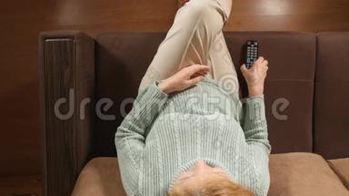 顶视图：老年妇女在家里的沙发上用遥控器换<strong>电视频道</strong>