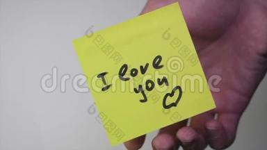 画画`我爱你`在黄纸上。 在白色背景上我爱你