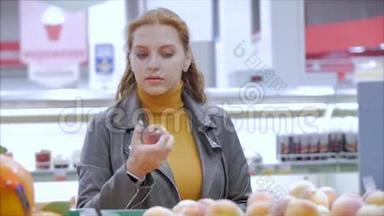 漂亮的年轻漂亮的红发女人在市场上，在超市里买食物、水果、苹果、西红柿、橘子