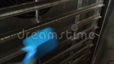 工人手中的蓝色刷子清洗工业烤箱。