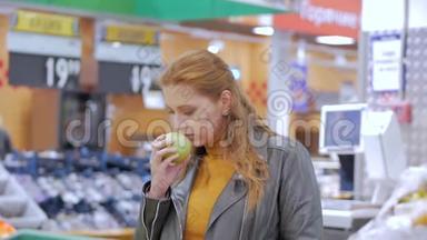漂亮的年轻漂亮的红发女人在市场上，在<strong>超市</strong>里买食物、<strong>水果</strong>、苹果。 女孩选择