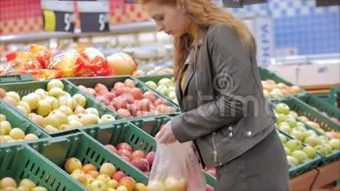 漂亮的年轻漂亮的红发女人在市场上，在超市里买食物、水果、<strong>苹果</strong>。 女孩选择