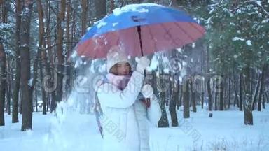 女孩站在树林里，转动落在雪中的伞