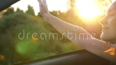 夏天坐汽车旅行的漂亮女人。 手玩风透过车窗的汽车.. 美丽的大自然。 慢节奏