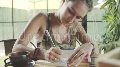 漂亮女人正在写日记，日记。 一杯咖啡在桌子上。