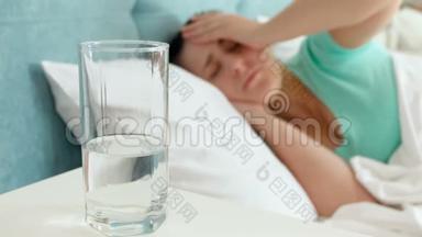 4k<strong>片头</strong>痛的年轻女子躺在床上，喝着玻璃水
