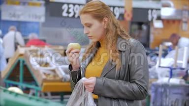 漂亮的年轻漂亮的红发女人在市场上，在<strong>超市</strong>里买食物、<strong>水果</strong>、苹果。 女孩选择