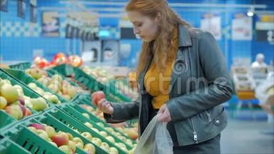 漂亮的年轻漂亮的红发女人在市场上，在超市里买食物、水果、<strong>苹果</strong>。 女孩选择产品