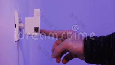 男子将Wi Fi中继器插入墙上的电插座，用手指按<strong>WPS</strong>按钮