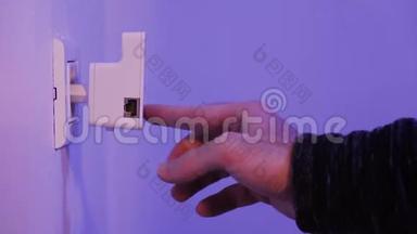 男子将Wi Fi中继器插入墙上的电插座，用手指按<strong>WPS</strong>按钮
