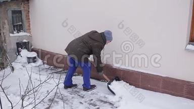 一位老年妇女打扫房子附近的雪铲