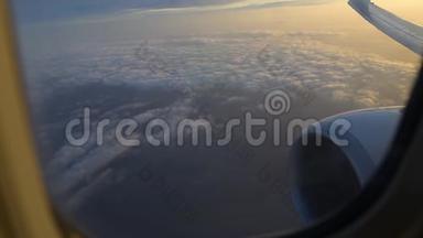 <strong>飞机机翼</strong>通过<strong>飞机</strong>窗口的视图。 日出时在云层上方飞行。