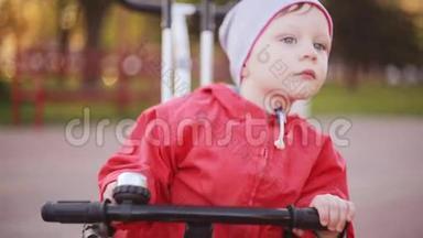 可爱的小男孩坐在自行车上，保持手在车轮上。 穿红色夹克准备骑自行车的孩子。