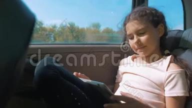 小女孩坐在车里，带着平板电脑，互联网，社交媒体<strong>去旅行</strong>。 汽车概念运动<strong>旅行</strong>运输
