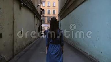 一个黑发女孩走在一条建筑物隧道里。 一个穿深蓝色裙子的女孩的背景。 慢莫，稳定射击