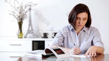 一个女人坐在桌子旁，用圆珠笔写字