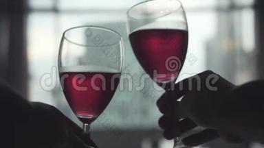 两个人在窗户边碰着一杯红<strong>酒</strong>，看着建筑城市的景色。 慢动作。 3840x2160，4k