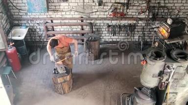 锻造中的胡子工铁匠用锤子在铁砧上制造金属工具，俯视