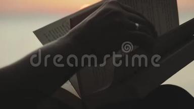 一个年轻女人坐在河边，在日落时读一本书的<strong>剪影</strong>，特写，慢<strong>动作</strong>。