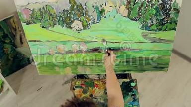 一个女人用调色板和画笔用<strong>油画</strong>颜料描绘<strong>风景</strong>。 顶部视图