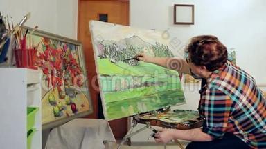 一个女人用调色板和画笔用油画颜料描绘风景。 投中弹