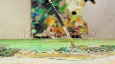 一个女人用调色板和画笔用油画颜料描绘风景。 顶部视图