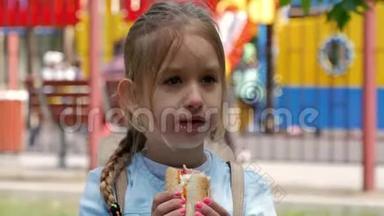 漂亮的年轻女孩在公园里<strong>吃热狗</strong>。