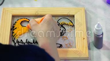 这位年轻艺术家的手在玻璃上用黄色颜料作画。