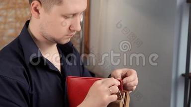 在车间里，一个男人正在缝制皮革工件，在做钱包