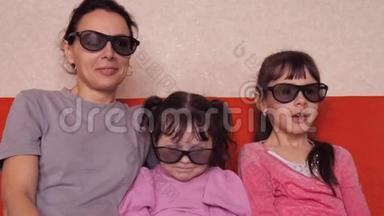 母亲带着两个女儿在沙发上用3D<strong>眼</strong>镜看电影。 家人在橙色沙发上看3D电影。