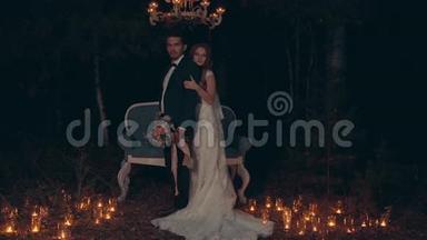 新郎和新娘在<strong>夜晚</strong>拥抱和亲吻，站在黑暗<strong>森林的</strong>沙发前。