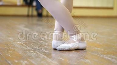 在芭蕾训练期间，一个穿白色芭蕾舞鞋的女孩`在一个旧木地板上的腿特写。 <strong>古典元素</strong>