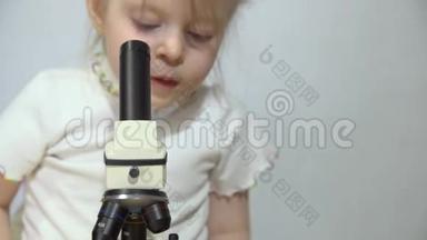 一个小女孩正在白墙旁边玩显微镜。