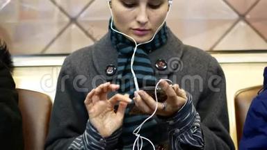 一个女孩在地铁车上听音乐或看智能手机上的视频