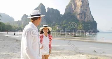 男主角情侣在沙滩上散步，手牵手在度假中与年轻游客交谈