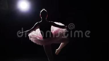年轻而优雅的芭蕾舞演员在她的尖角芭蕾舞鞋上在黑色背景在工作室跳舞。 女子表演经典芭蕾