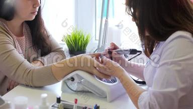 美容店的五金修甲特写镜头。 美甲医生正在用电指甲锉刀修指甲